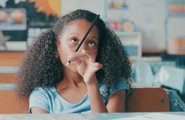 小女孩在学校盯着铅笔
