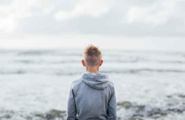 young boy staring out into the ocean